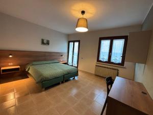 a bedroom with a bed and a table and windows at Corte Valdadige in Brentino Belluno