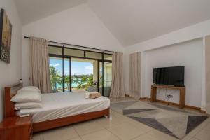 a bedroom with a bed and a tv and a window at 4- Bedroom Beachfront Villa in Grand Baie