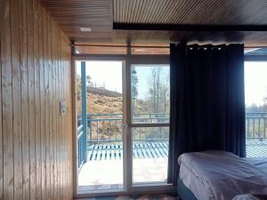a bedroom with a bed and a sliding glass door at Silver Dew Resorts and Restaurant in Dhanaulti