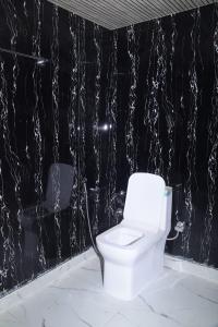 a white toilet in a bathroom with a black wall at Silver Dew Resorts and Restaurant in Dhanaulti