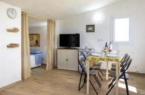 La Mansarda sul Verde في شاكا: غرفة معيشة مع طاولة مع كراسي وتلفزيون