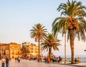 La Mansarda sul Verde في شاكا: مجموعة من الناس يمشون في شارع فيه نخيل