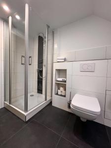 a white bathroom with a shower and a toilet at Hotel Restaurant Wolfsschlucht GmbH in Bad Münstereifel