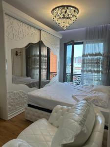 ein weißes Schlafzimmer mit einem großen Bett und einem Kronleuchter in der Unterkunft tirana delijorgjis appartment in Tirana