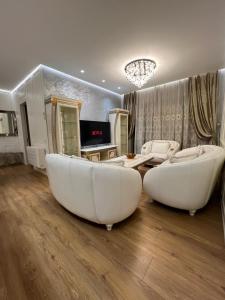 ein Wohnzimmer mit zwei weißen Stühlen und einem Sofa in der Unterkunft tirana delijorgjis appartment in Tirana