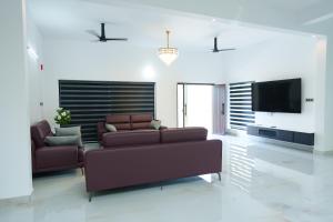 a living room with a couch and a flat screen tv at KiwiOz Villa in Thamarassery