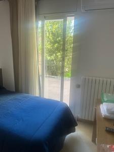 a bedroom with a blue bed and a large window at hostal trevol in Torelló