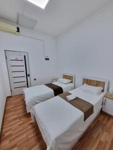 two beds in a room with white walls and wooden floors at shafranhotel in Tashkent