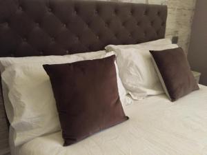 a bed with white pillows and a brown headboard at 29 Venti Luxury in Palermo