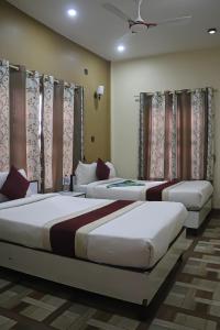 3 posti letto in una camera con tende e finestre di Hotel Flycatcher Chitwan- A jungle Safari Home a Sauraha