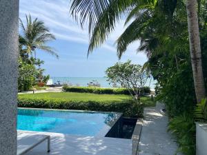 a swimming pool with palm trees and the ocean at Luxuriously private seafront Bangtao beach in Surin Beach