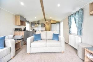 a living room with a white couch and blue pillows at Hope View - Ashbourne Heights Holiday Park in Fenny Bentley