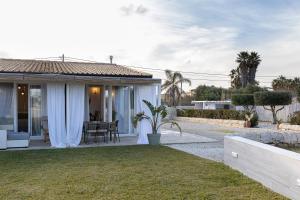 una casa con cortinas blancas y un patio en Villa Elysian con piscina privata, en Marzamemi