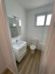 a white bathroom with a toilet and a sink at Maison centre de Barfleur in Barfleur