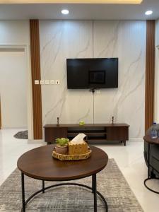 a living room with a table and a tv at نسيم سلطانة in Al Madinah