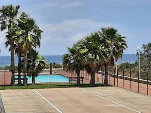 a tennis court with palm trees next to a pool at La Manga beach has everything in San Javier