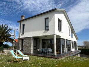 a white house with two chairs and a table at Casa El Lloréu in Naves