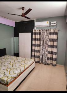 a bedroom with a bed with a ceiling fan and curtains at Shanti valley homestay in Guwahati