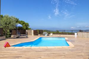 a swimming pool in a patio with a table and an umbrella at Villa Luna e' Pedra - Suites Esclusive in Villa con Vista sulla Baia di Alghero e Piscina, Jacuzzi privata in Alghero