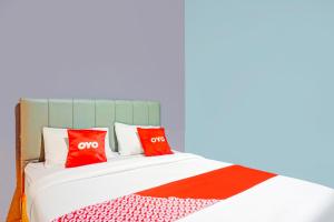 a bed with two red pillows on it at Hotel O Mandala Near Universitas Negeri Medan ( UNIMED ) in Medan