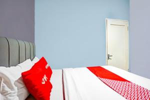 a bedroom with a bed with red and white pillows at Hotel O Mandala Near Universitas Negeri Medan ( UNIMED ) in Medan +19 photos