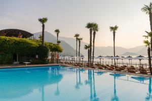 a large swimming pool with chairs and palm trees at Grand Hotel Villa Serbelloni - The only Relais & Châteaux on Lake Como in Bellagio