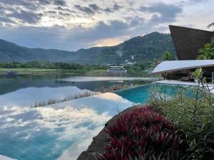 a swimming pool next to a body of water at Tranquil lake view villa on Phuket golf estate in Kathu