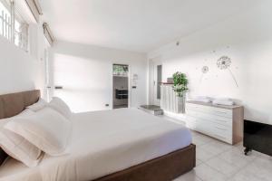 a white bedroom with a large bed and a dresser at Montorfano Garden & Lake View by Quokka 360 - Villa near Lake Como in Montorfano