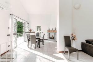 a white living room with a table and chairs at Montorfano Garden & Lake View by Quokka 360 - Villa near Lake Como in Montorfano