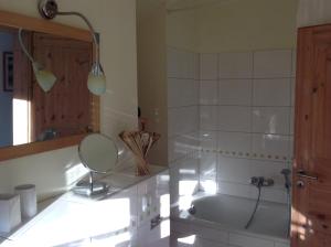ein Badezimmer mit einer Badewanne, einem Spiegel und einem Waschbecken in der Unterkunft Ferienwohnung Geißler in Radebeul