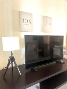 a flat screen tv sitting on a table with a lamp at Casa Santi Il silenzio tra lago e montagna in Toscolano Maderno