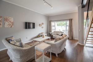 Una sala de estar con sillas de mimbre y una mesa. en Seaside Escape at The Dunes: Walk to Beach Braai, en Plettenberg Bay