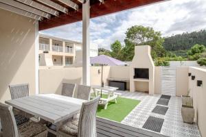 Un patio con una mesa y sillas en una terraza. en Seaside Escape at The Dunes: Walk to Beach Braai, en Plettenberg Bay