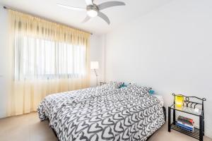 a bedroom with a black and white bed with a ceiling fan at Apartamento bajo luxury golf Baviera Hills 54 in Caleta De Velez +23 photos