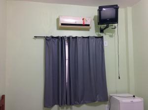 a bathroom with a shower curtain and a tv at Hotel Toraryca in Belém