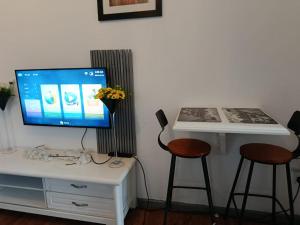 a living room with a tv and a table and stools at Woods Cottage Kilimani in Nairobi