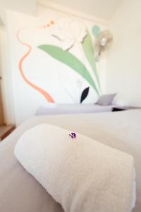 a towel on a bed with a flower on it at Ocean Nomads Coworking in Arona