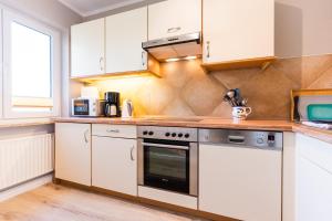 eine Küche mit weißen Schränken und einem Herd mit Backofen in der Unterkunft Am Hof 3 in Staberdorf