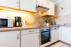 eine Küche mit weißen Schränken und einer Mikrowelle in der Unterkunft Am Hof 3 in Staberdorf