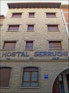 un edificio de ladrillo con un cartel encima en Hostal Serruchi, en Teruel