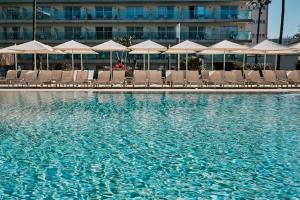 a pool with chairs and umbrellas in front of a hotel at Helios Mallorca Hotel & Apartments in Can Pastilla