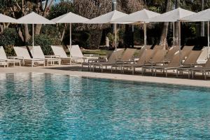 a group of chairs and umbrellas next to a swimming pool at Helios Mallorca Hotel & Apartments in Can Pastilla