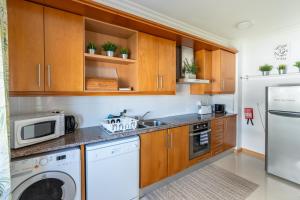 a kitchen with wooden cabinets and a washer and dryer at Sam's House in Foz do Arelho