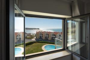 a room with a window with a view of the ocean at Sam's House in Foz do Arelho