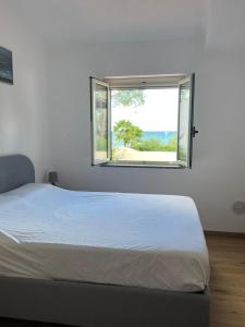Un dormitorio blanco con una cama y una ventana. en Villa Edith, en Parghelia