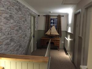 a hallway with a stone wall and a lamp on a desk at The Harbour Guest House in Irvine