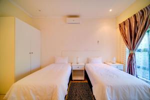 two beds in a room with a window at Mshengu Kruger Lodge in Marloth Park +22 photos