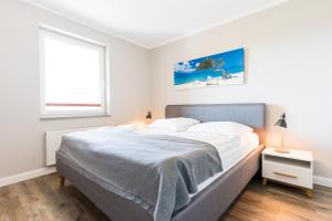 a white bedroom with a large bed and a window at Fehmarnstrand 77 Whg 2 in Staberdorf