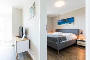 a bedroom with a bed and a desk with a tv at Fehmarnstrand 77 Whg 2 in Staberdorf