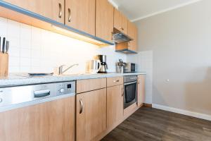 a kitchen with wooden cabinets and a sink at Fehmarnstrand 77 Whg 2 in Staberdorf